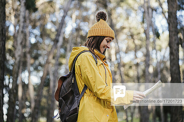 Lächelnde Frau  die eine Karte liest  während sie im Wald unterwegs ist