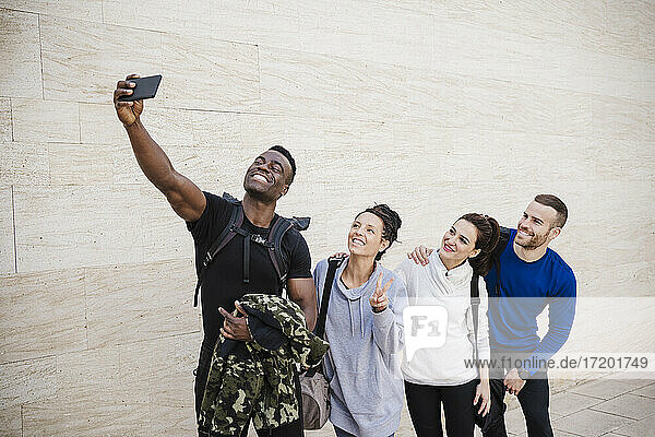 Lächelnde männliche und weibliche Freunde nehmen Selfie durch Handy auf Gehweg