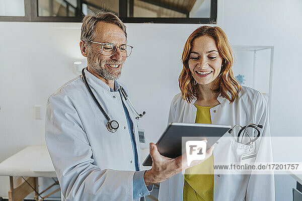 Smiling coworker using digital tablet while standing at clinic