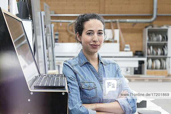 Confident businesswoman standing by control panel at factory