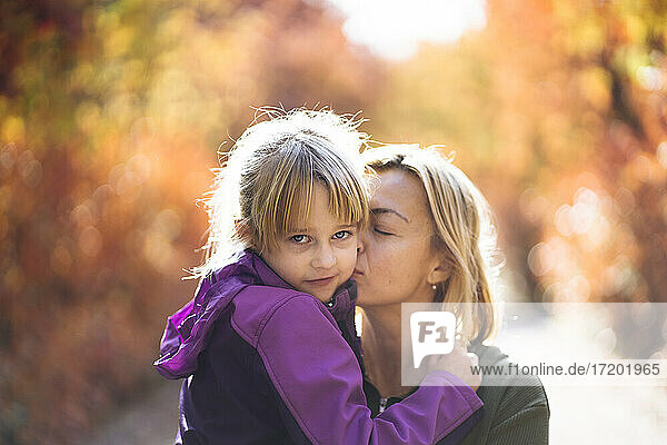 Mutter küsst süße Tochter auf die Wange im Park