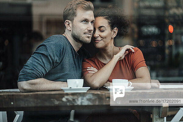 Geschäftsfrau lehnt sich an einen Mann  während sie im Cafe sitzt
