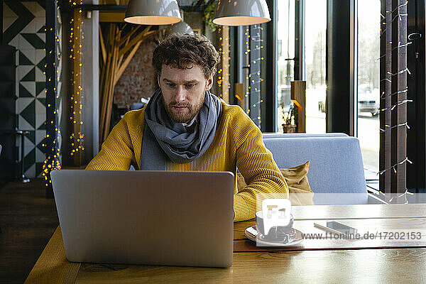 Geschäftsmann trinkt Kaffee und arbeitet am Laptop in einem Café