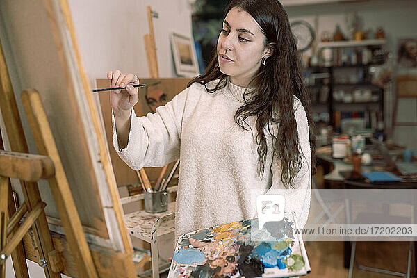 Weibliche Künstlerin malt auf Leinwand in einem Kunstatelier