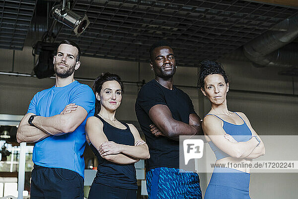 Multi-ethnic group of sports people with arms crossed standing in gym