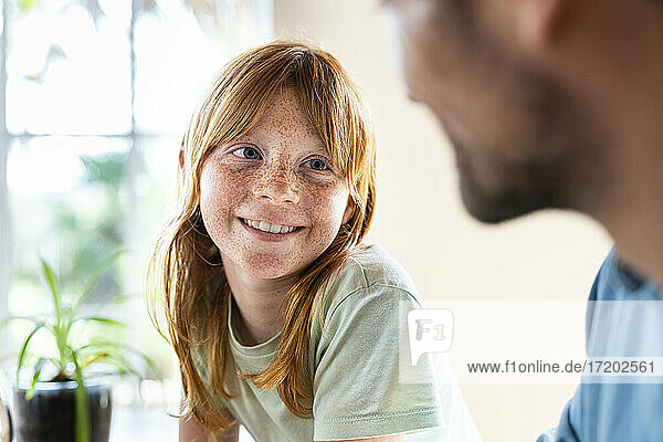 Niedliches rothaariges Mädchen lächelt ihren Vater an