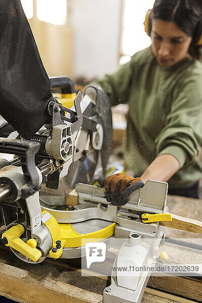 Handwerkerin bei der Arbeit mit Maschinen an einer Werkbank in einer Werkstatt