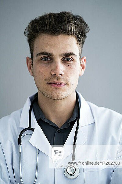 Hübscher männlicher Arzt vor grauer Wand im Krankenhaus