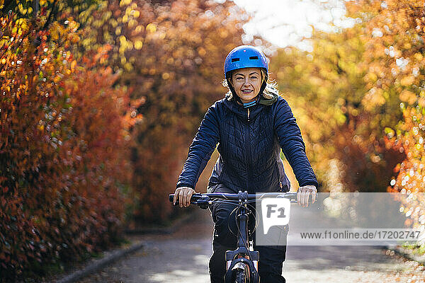 Glückliche Frau mit Helm auf dem Fahrrad im Park