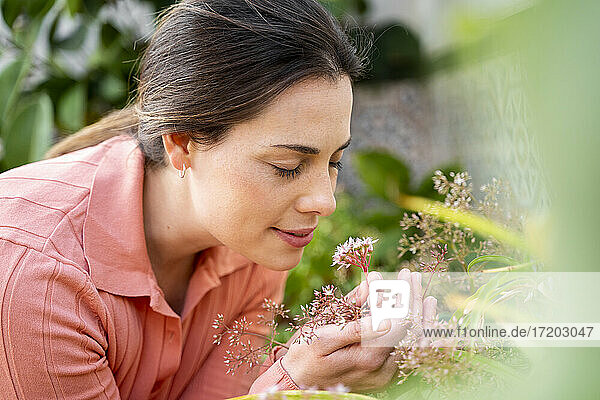 Junge Frau riecht an frischen Blumen im Garten