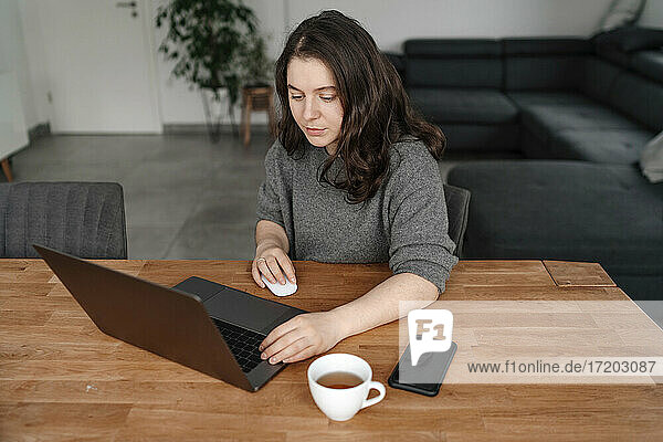 Unternehmerin arbeitet am Laptop am Tisch im Wohnzimmer