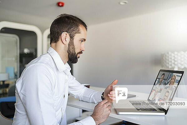 Unternehmer bespricht sich per Videokonferenz über Laptop im Büro mit seinem Team
