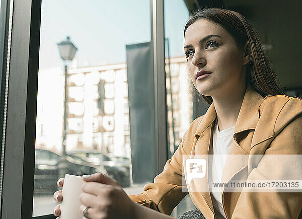 Schöne Frau sitzt am Glasfenster eines Cafés