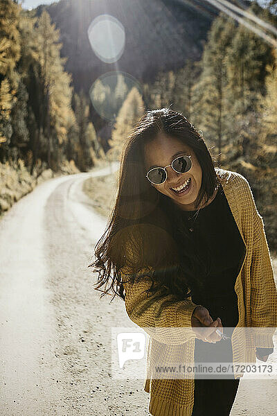 Junge Frau mit Sonnenbrille und Zigarette in der Hand auf einem Waldweg