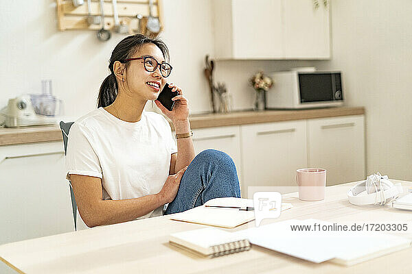Young woman talking on mobile phone while sitting at home