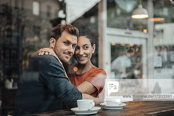Paar lächelnd  während umarmt einander beim Sitzen im Café