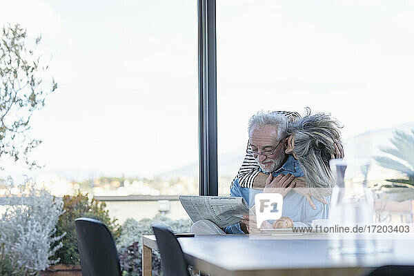 Ältere Frau turtelt mit einem Mann  während sie zu Hause am Fenster steht