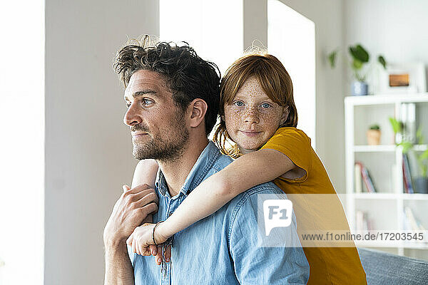 Tochter mit blauen Augen umarmt Vater im Wohnzimmer
