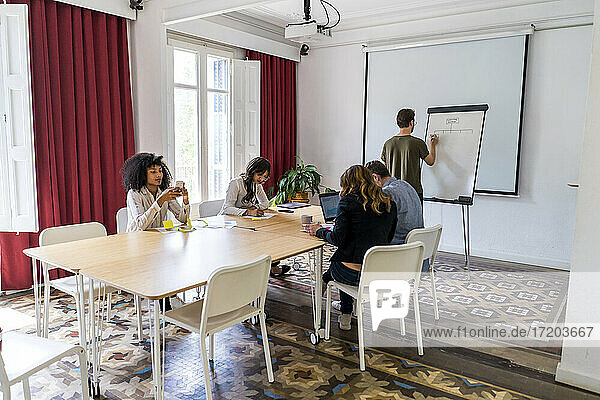 Männliche und weibliche Unternehmer diskutieren an einem Konferenztisch im Büro