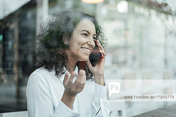 Young businesswoman smiling while talking on mobile phone sitting at cafe