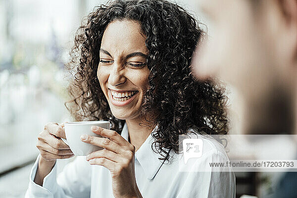 Fröhliche Geschäftsfrau  die mit einem Kollegen Kaffee trinkt  während sie in einem Cafe sitzt