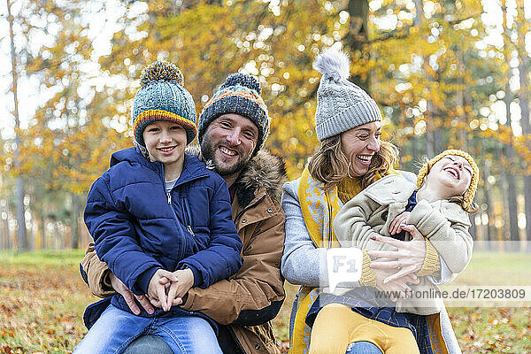 Cheerful parents smiling while sitting with children at forest