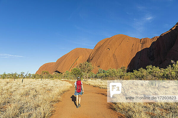 Australien  Northern Territory  Rückansicht einer Frau beim Wandern durch die Wüstenlandschaft des Uluru Kata Tjuta National Park