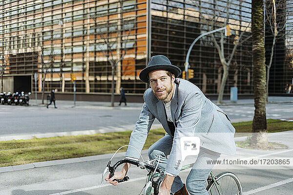 Geschäftsmann mit Hut auf dem Fahrrad in der Stadt