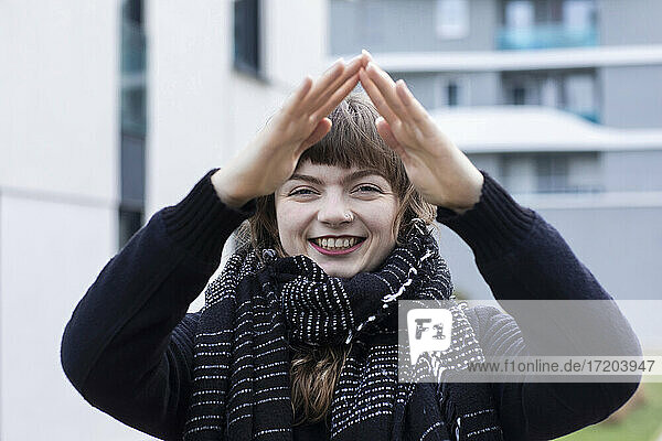 Junge Frau lächelt  während sie in der Stadt stehend ein Hausschild gestikuliert