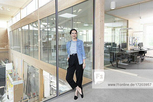 Businesswoman leaning on glass wall in factory