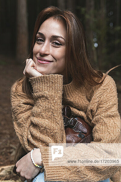Fröhliche Frau lächelt  während sie im Wald sitzt