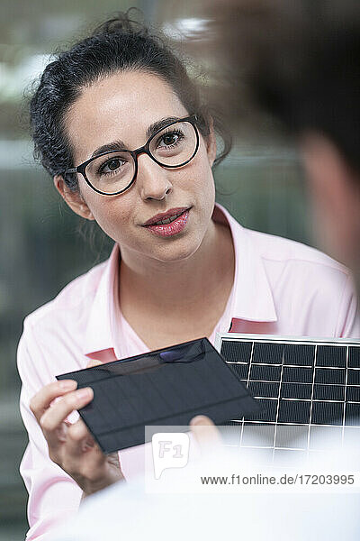 Unternehmerin mit Solarmodell  die einen männlichen Kollegen im Büro betrachtet