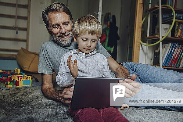 Happy father with son video calling on digital tablet at home