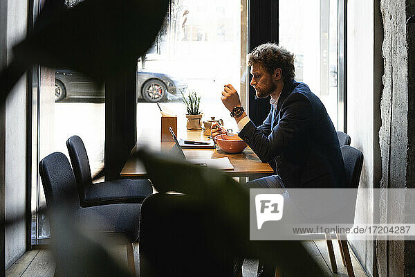 Geschäftsmann beim Essen im Café sitzend