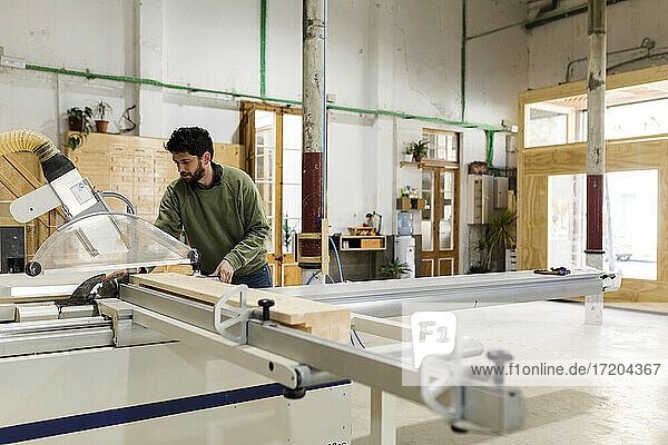 Männlicher Tischler bei der Arbeit mit einer Tischsäge in einer Werkstatt