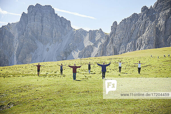 Multiethnische Männer und Frauen üben an einem sonnigen Tag Yoga am Berg
