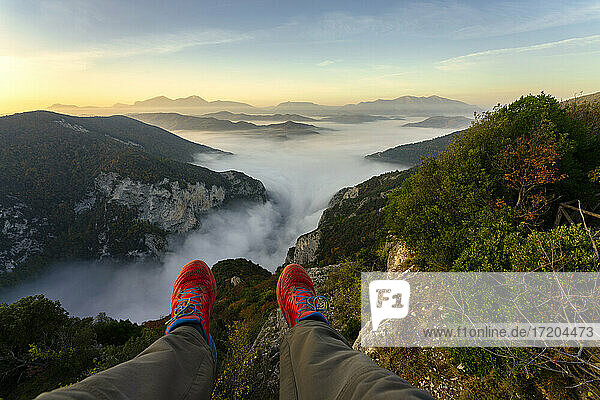 Mann auf einem Berg sitzend gegen den Himmel bei Sonnenaufgang in der Furlo-Schlucht  Marken  Italien