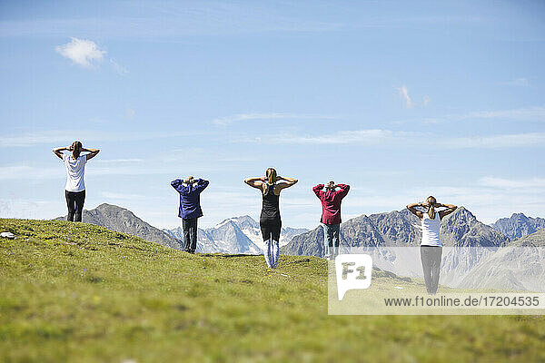 Kaukasischer Mann und Frauen üben Yoga vor einem Berg