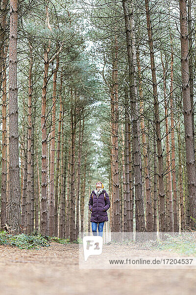 Frau mit Händen in den Taschen geht im Wald spazieren
