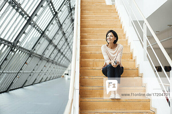 Nachdenkliche Geschäftsfrau  die auf einer Treppe im Korridor sitzt