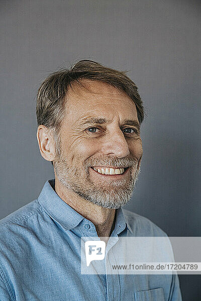 Smiling man with gray eyes on gray background