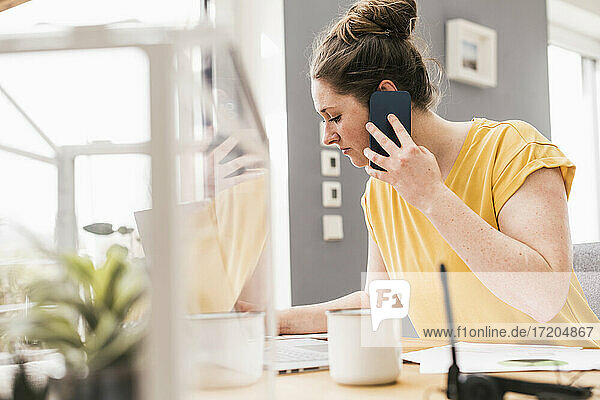 Unternehmerin bei der Arbeit  während sie mit ihrem Smartphone telefoniert
