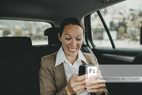 Aufgeregte weibliche Fachkraft  die während der Fahrt im Taxi telefoniert