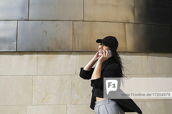 Lächelnde Frau mit Mütze  die mit einem Smartphone telefoniert