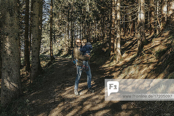 Mature man carrying son while standing in forest at Salzburger Land  Austria