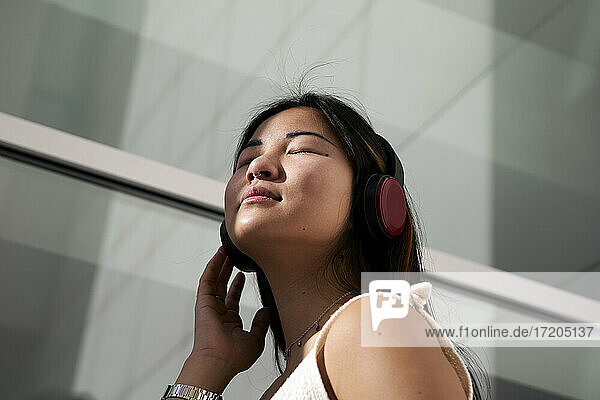 Asiatische Frau hört Musik über Kopfhörer im Freien