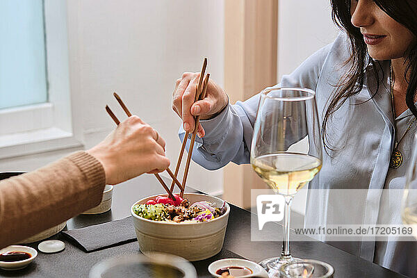 Female customer having food with chopsticks at restaurant
