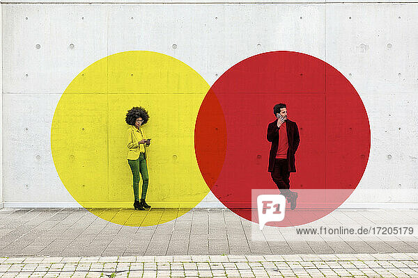 Two overlapping circles visualizing social distancing covering man and woman standing outdoors with smart phones in hands