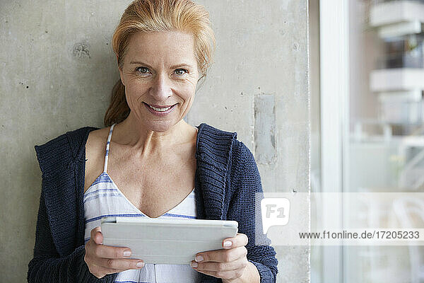 Frau mit digitalem Tablet an der Wand zu Hause