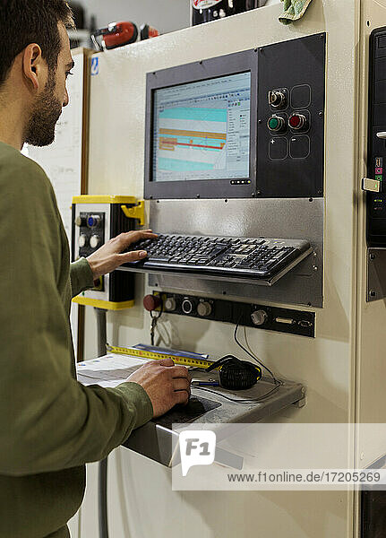 Junger männlicher Tischler  der eine CNC-Maschine in einer Werkstatt bedient
